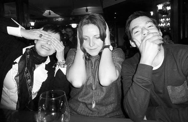 Three people in a pub doing 3 Wise Monkeys