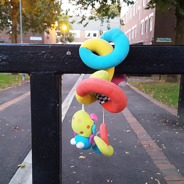Brightly coloured snake, bug and snail cuddly toy hanging on a railing