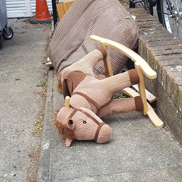 Knocked over rocking horse on the pavement