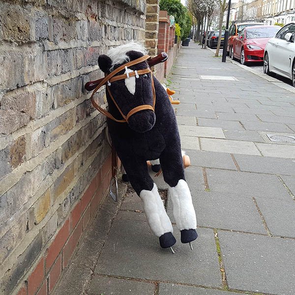 Abandoned, unwanted, unloved, cuddly toy - Cuddly, brown rocking horse, without the rockers, casually leaning against a brick wall, on the Pavement