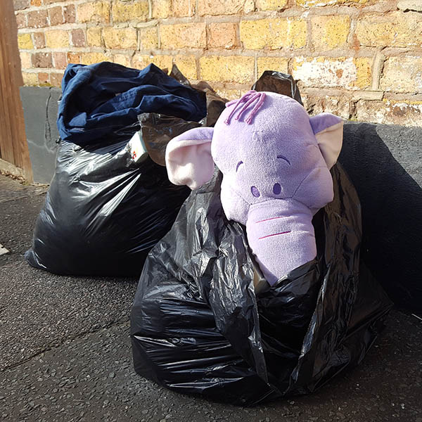 Abandoned, unwanted, unloved, cuddly toy - Cuddly elephant peeping out of a bin bag on the pavement