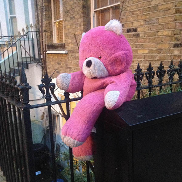 Abandoned, unwanted, unloved, cuddly toy - Large, pink teddybear, sat on a telephone wire box, leaning against a railing
