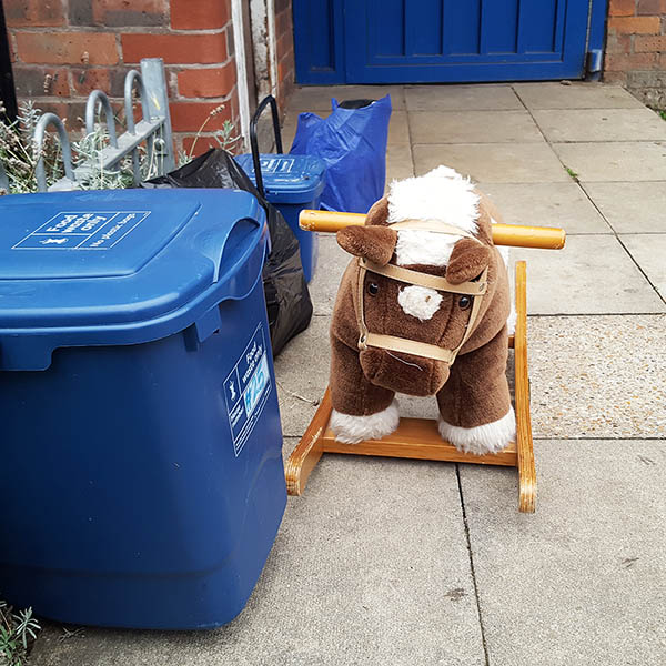 Abandoned, unwanted, unloved, cuddly toy - Cuddly rocking horse beside recycling bins outside flats