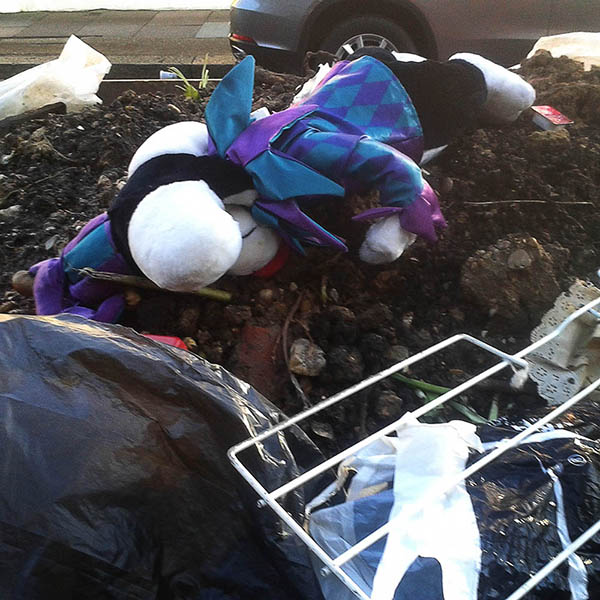Abandoned, unwanted, unloved, cuddly toy - Cuddly Snoopy dog, face down on a Skip, dressed as a jester
