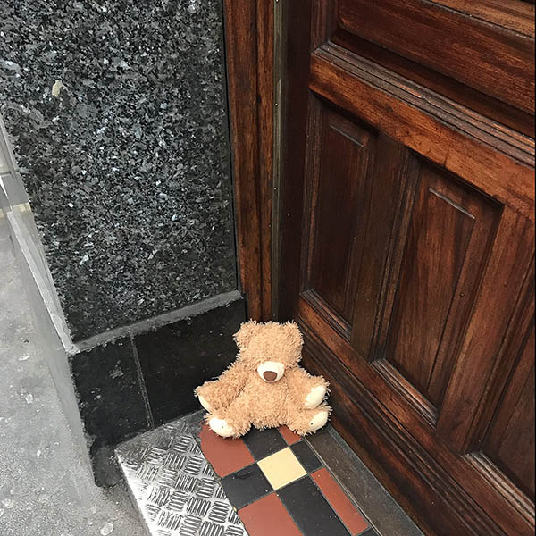 Abandoned, unwanted, unloved, cuddly toy - Small teddybear sat in the corner of a big doorway