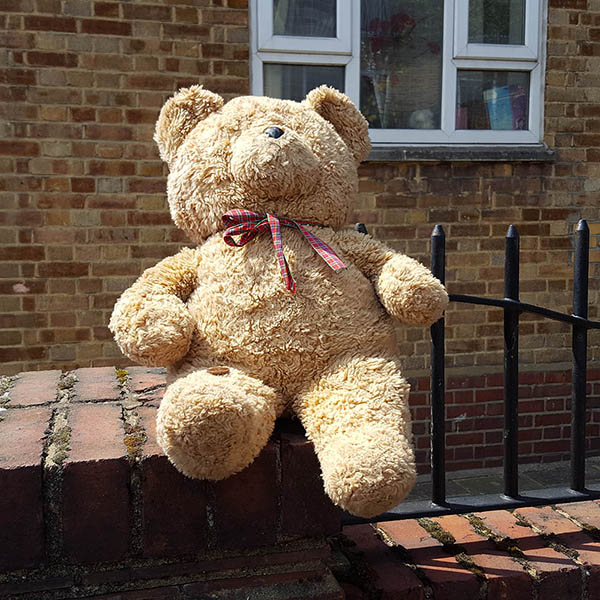 Abandoned, unwanted, unloved, cuddly toy - Teddybear with a two pence coin, sitting on a wall, outside a block of flats