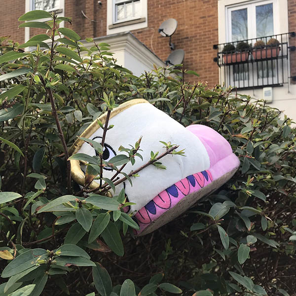 Abandoned, unwanted, unloved, cuddly toy - Huge slipper shaped thing with a face, thrown into some bushes in front of flats