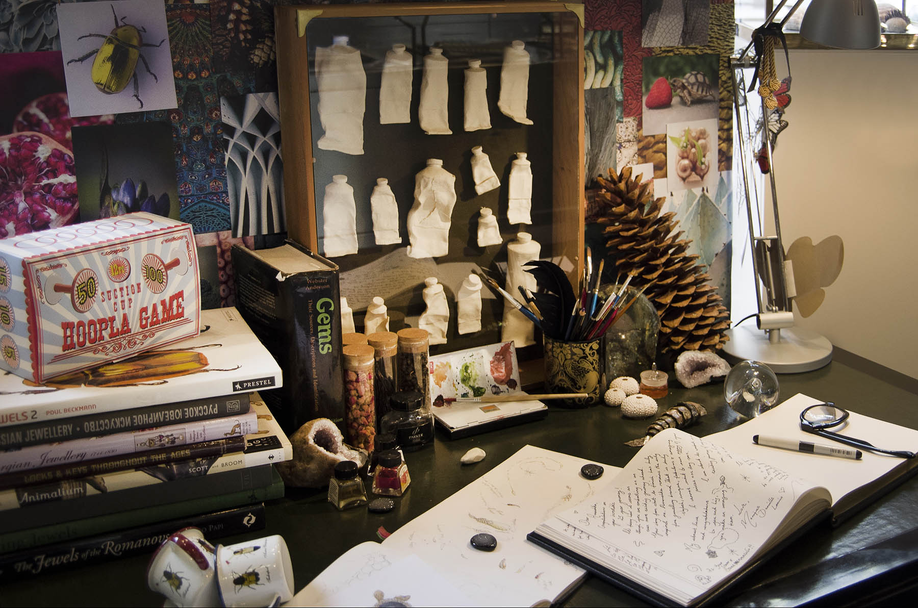 Annoushka Milestones Exhibition - desk with books, hoopla, large pine cone, paints, paint brushes, sketchbooks