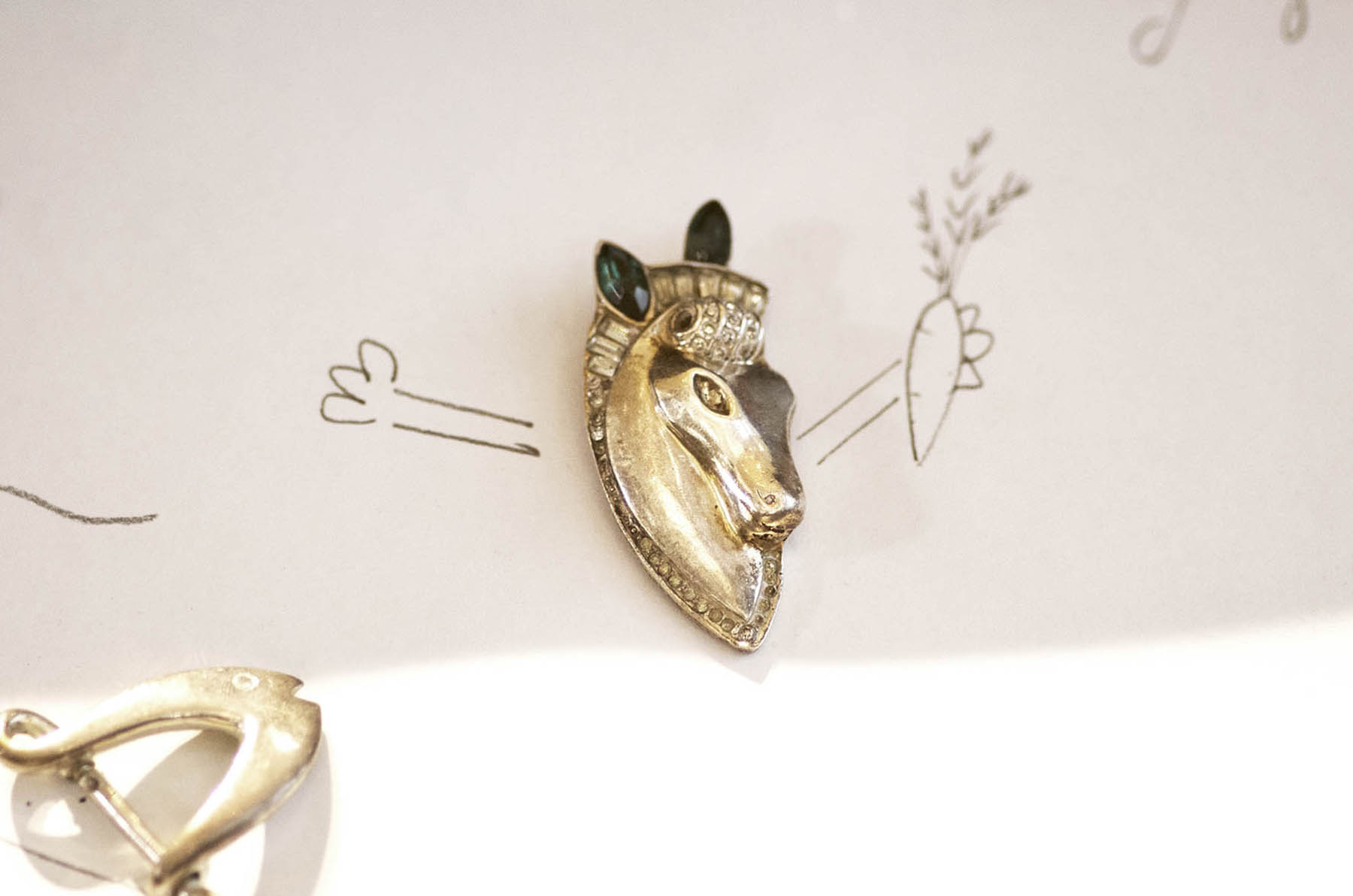 Annoushka Milestones Exhibition display cabinet - mother's horse brooch laid on paper with doodles 
