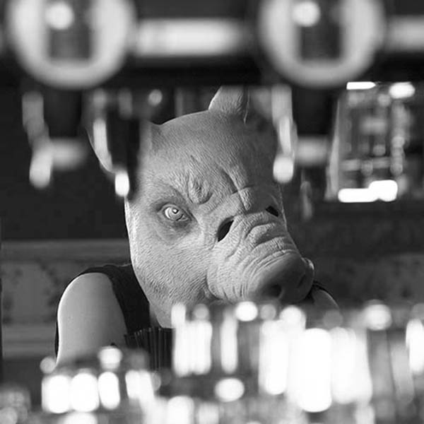 Person in a pig mask sitting in a bar