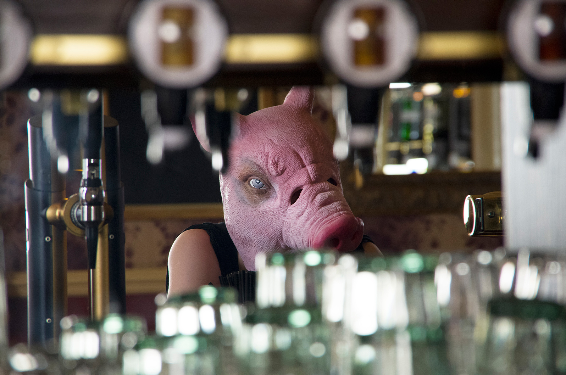 Beast - person wearing pig mask looking in pub mirror