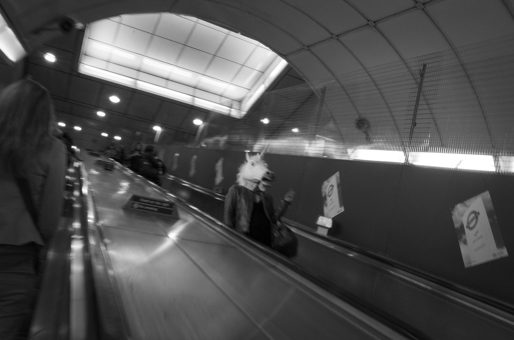 Beast - person wearing unicorn mask on tube escalator