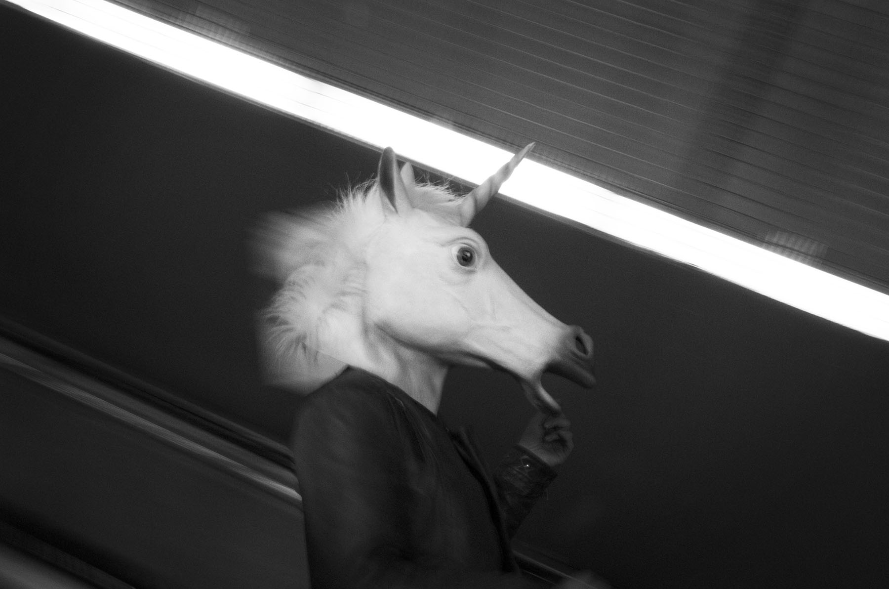 Beast - close up of person wearing unicorn mask on tube escalator