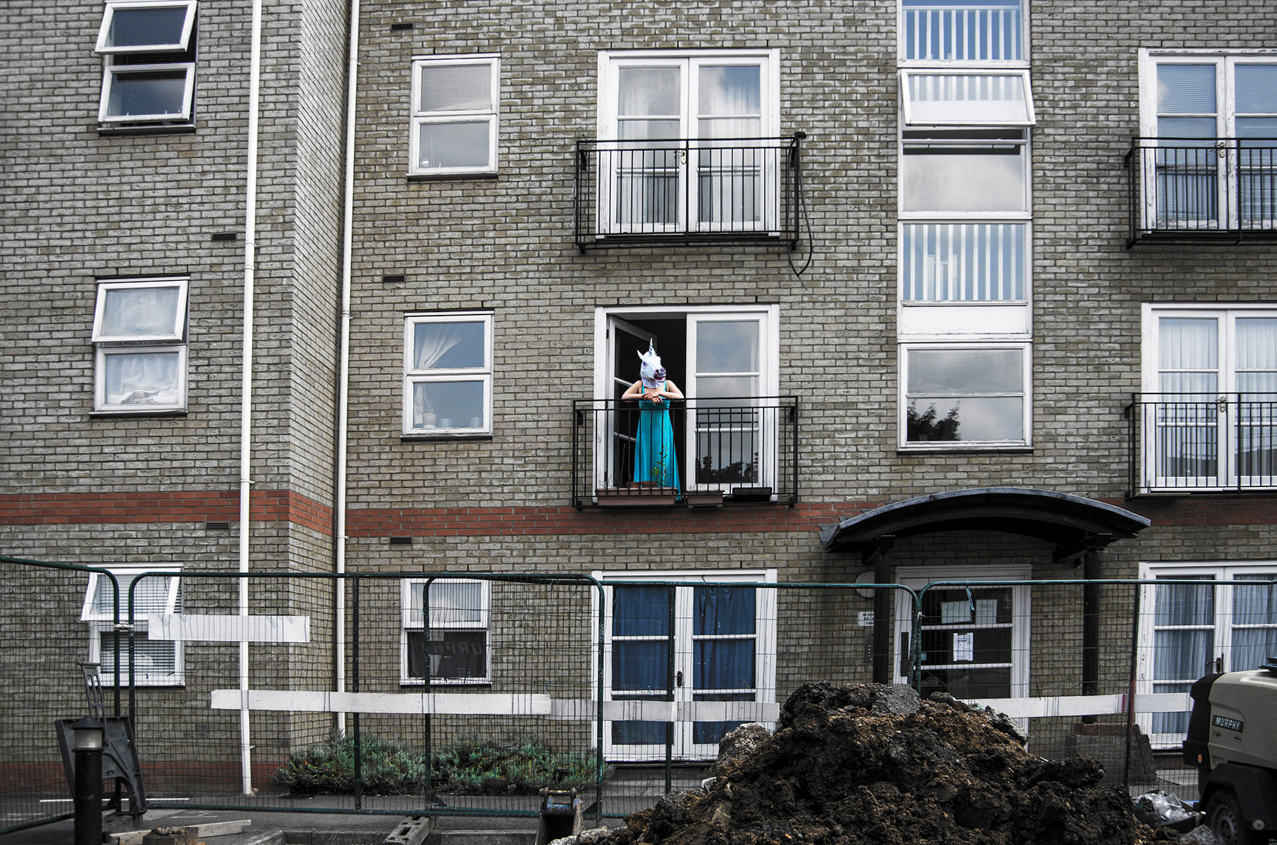 Beast - block of flats with person wearing unicorn mask on balcony