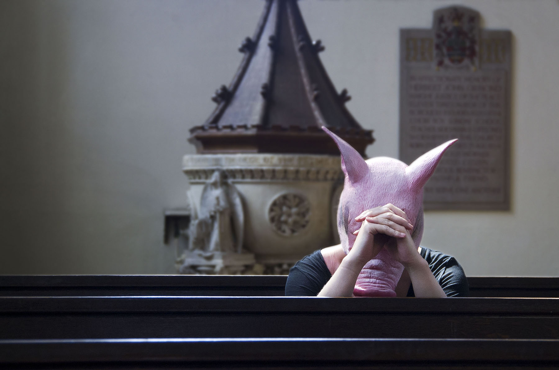 Beast - person wearing pig mask praying in church