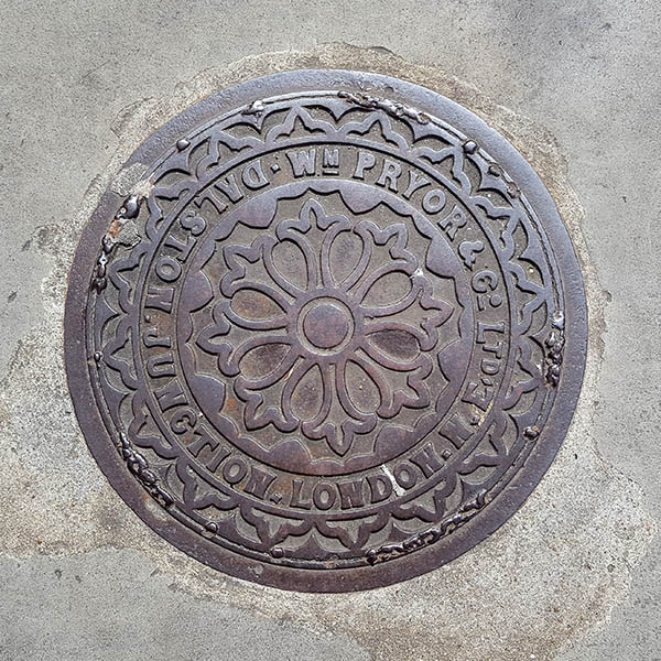 Manhole Cover, London - Cast iron with decorative circular fleur dis lis pattern Inscribed with WM PRYOR & Co Ltd Dalston Junction London NE