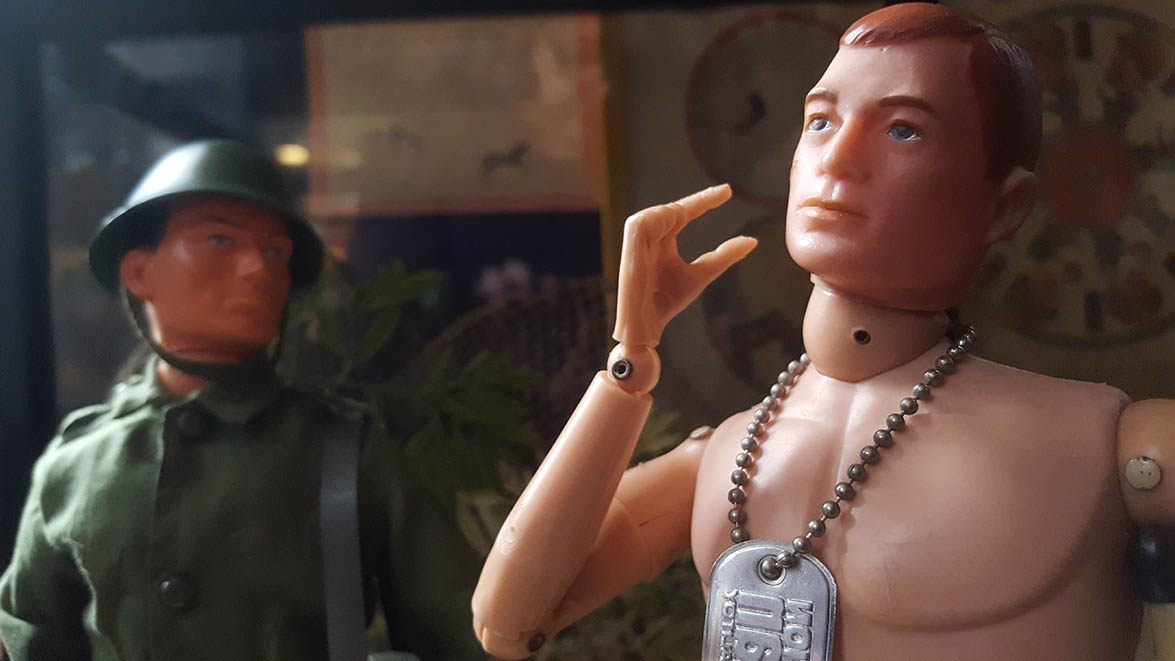 Bare chested Action Man looks to the distance whilst Action Man in army uniform looks towards him displayed in Pollocks Toy Museum