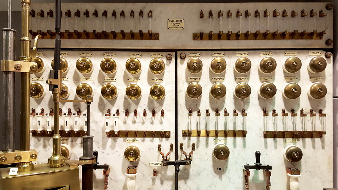 Multiple brass light switches and glass tubes displayed in glass cabinets in The Science Museum