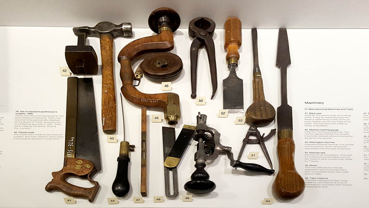 Assortment of old woodworking tools displayed in glass cabinets in The Science Museum