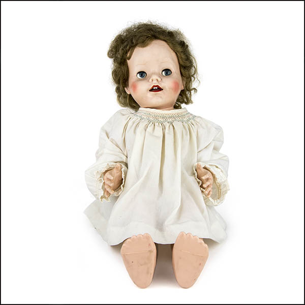 Vintage hard plastic doll wearing white smock dress