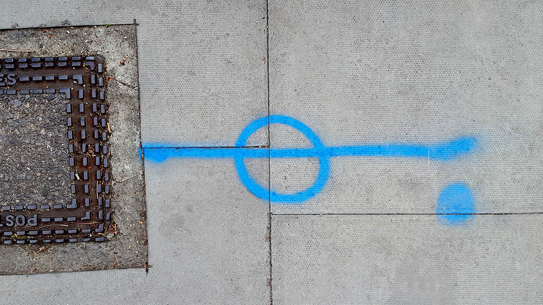 Pavement markings - spray painted squiggles on paving stones - Blue vertical line circle and dot