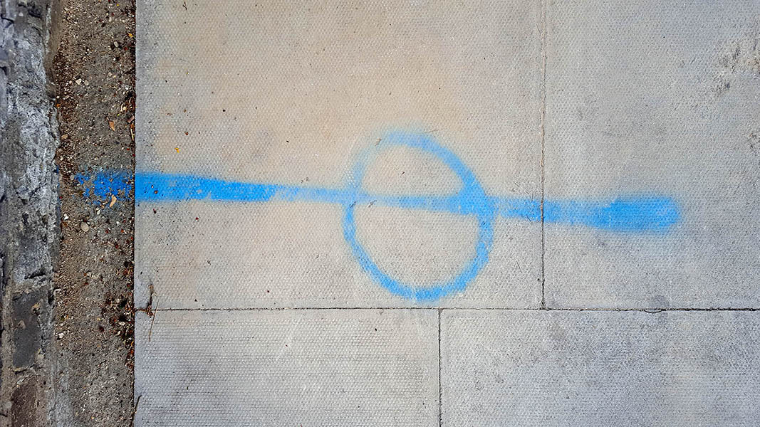 Pavement markings - spray painted squiggles on paving stones - Blue horizontal line and circle