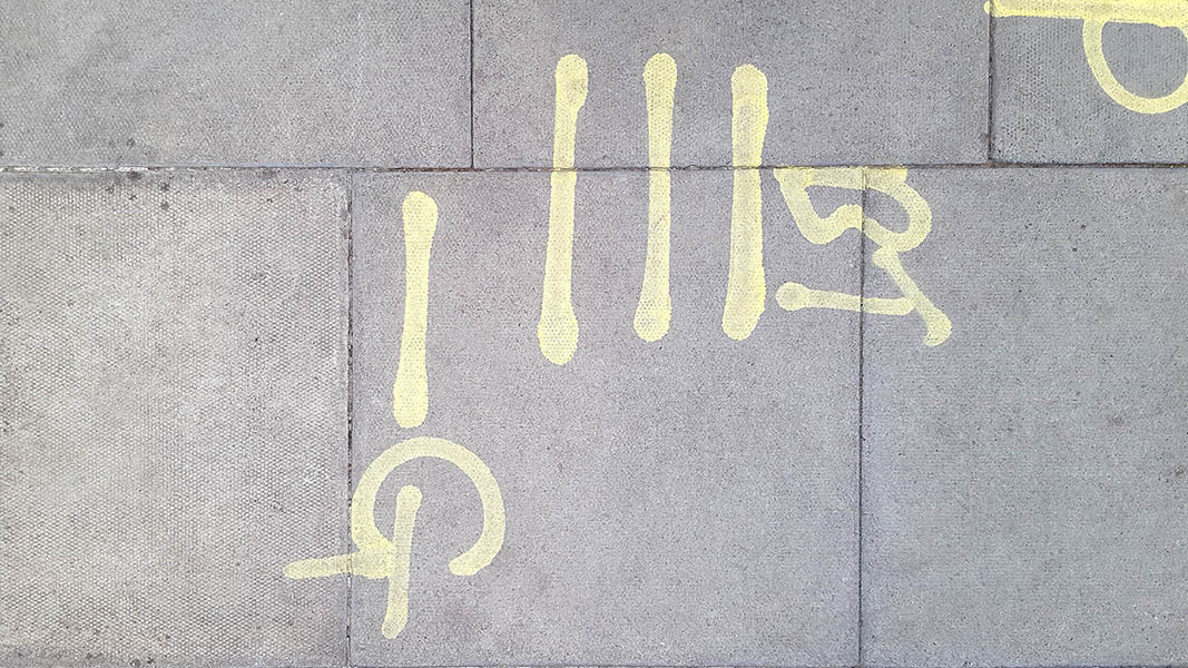 Pavement markings - spray painted squiggles on paving stones - Yellow vertical lines and letters