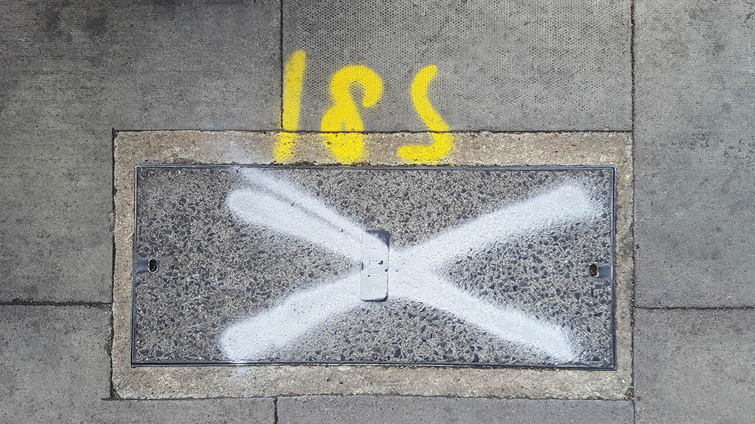 Pavement markings - spray painted squiggles on paving stones - Big white X and yellow numbers 185