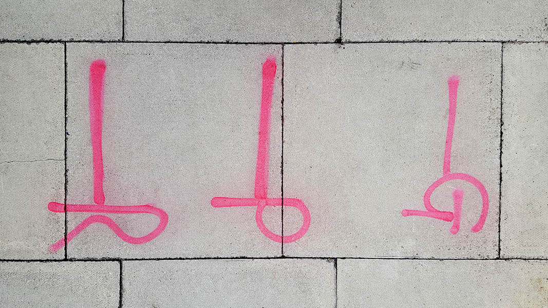 Pavement markings - spray painted squiggles on paving stones - Red vertical lines and the letters GPR