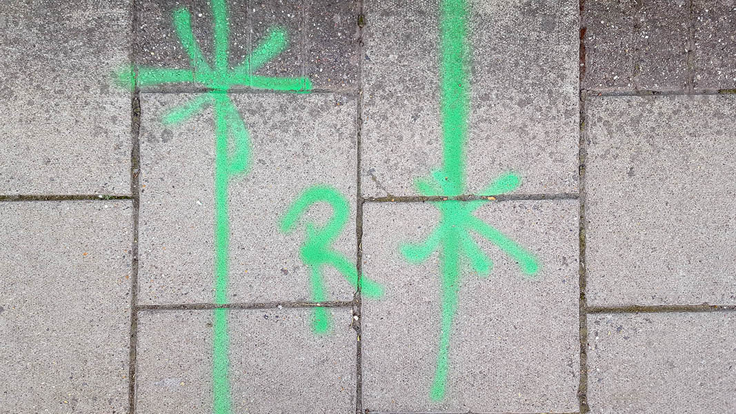 Pavement markings - spray painted squiggles on paving stones - Green vertical lines asterix and the letter R