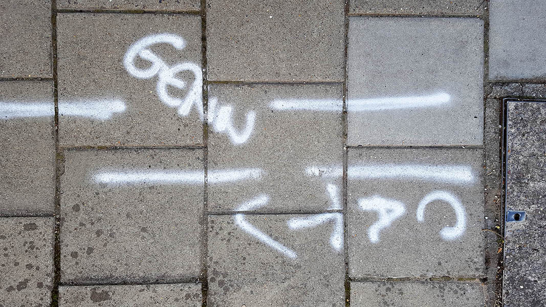 Pavement markings - spray painted squiggles on paving stones - Whit horizontal lines and letters