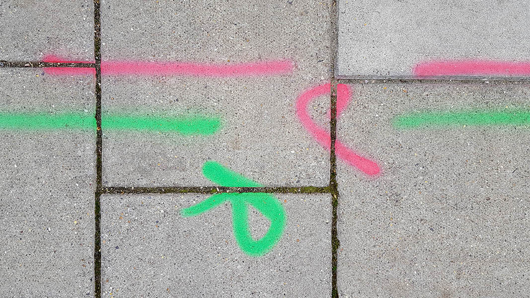 Pavement markings - spray painted squiggles on paving stones - Red and green horizontal lines and the letters JR