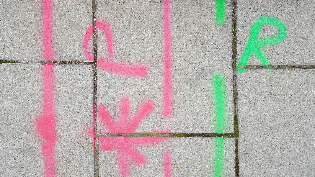 Pavement markings - spray painted squiggles on paving stones - Red and green horizontal lines asterix and the letters PR