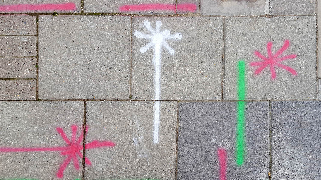 Pavement markings - spray painted squiggles on paving stones - Red green white lines and asterix
