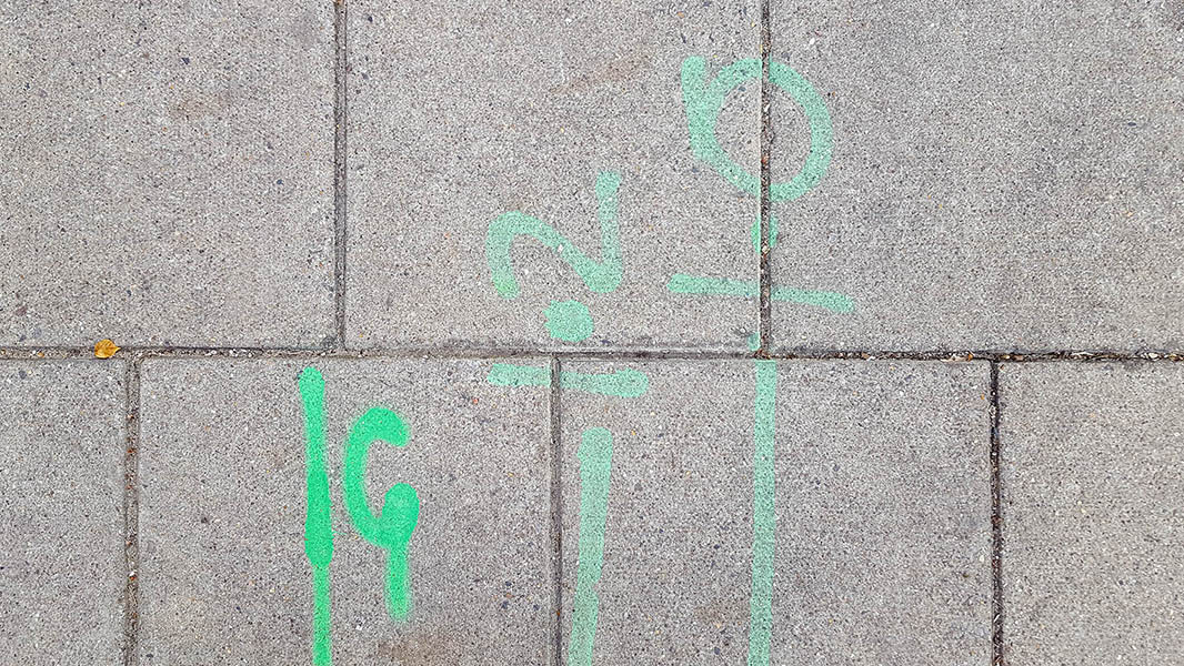 Pavement markings - spray painted squiggles on paving stones - Green vertical lines numbers and letters