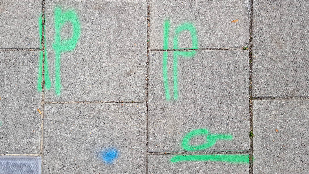 Pavement markings - spray painted squiggles on paving stones - Green lines and letters