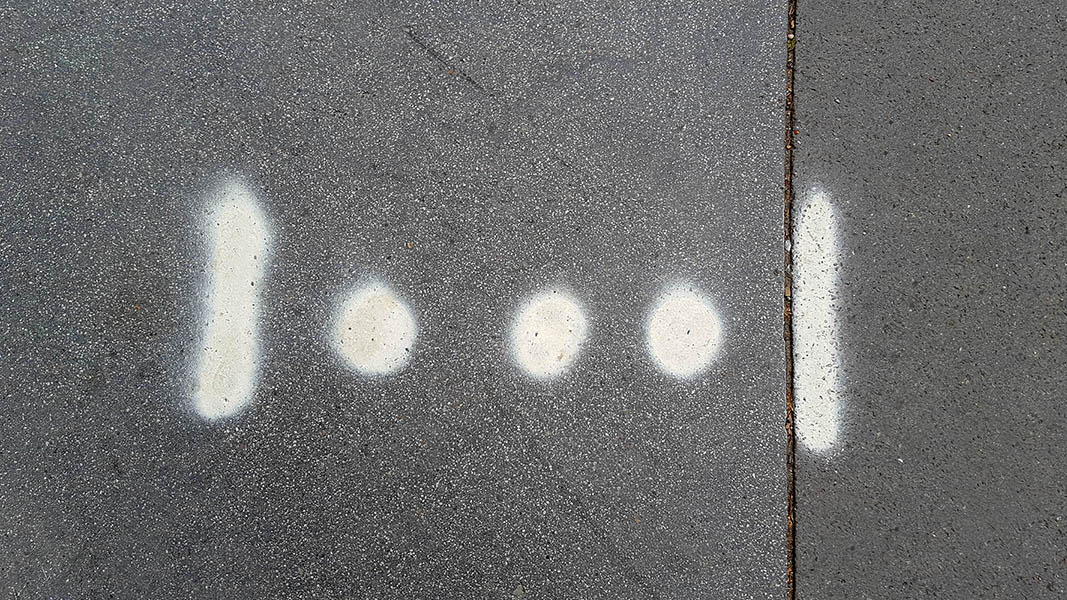 Pavement markings - spray painted squiggles on paving stones - 2 white vertical lines and 3 dots