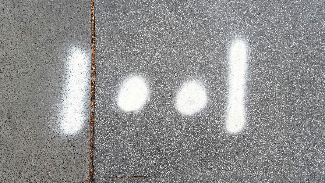Pavement markings - spray painted squiggles on paving stones - 2 white vertical lines and 2 dots