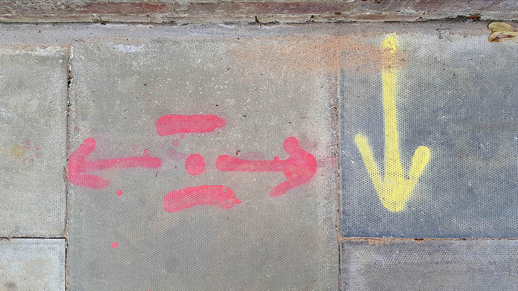 Pavement markings - spray painted squiggles on paving stones - Red and yellow arrows