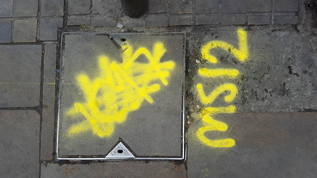 Pavement markings - spray painted squiggles on paving stones - Yellow squiggles and letters