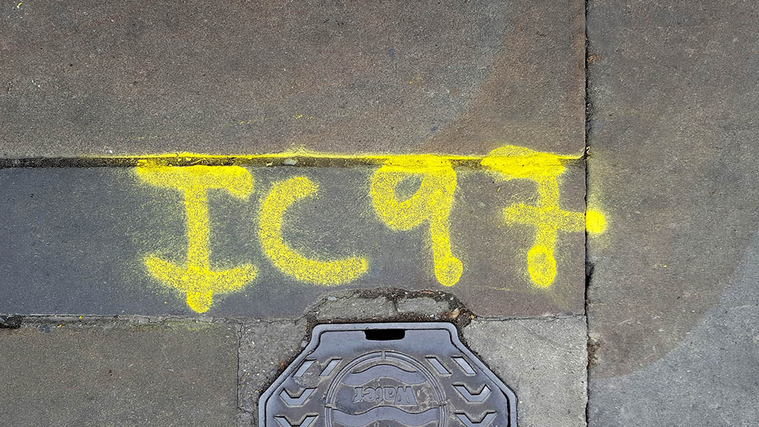 Pavement markings - spray painted squiggles on paving stones - Yellow letters and numbers
