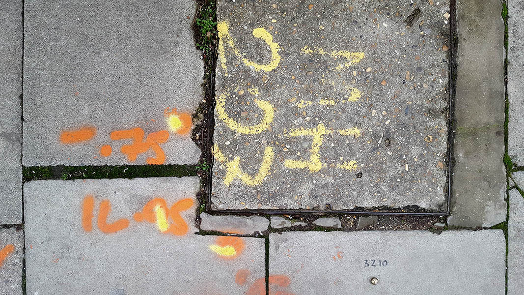 Pavement markings - spray painted squiggles on paving stones - Orange and yellow letters and words