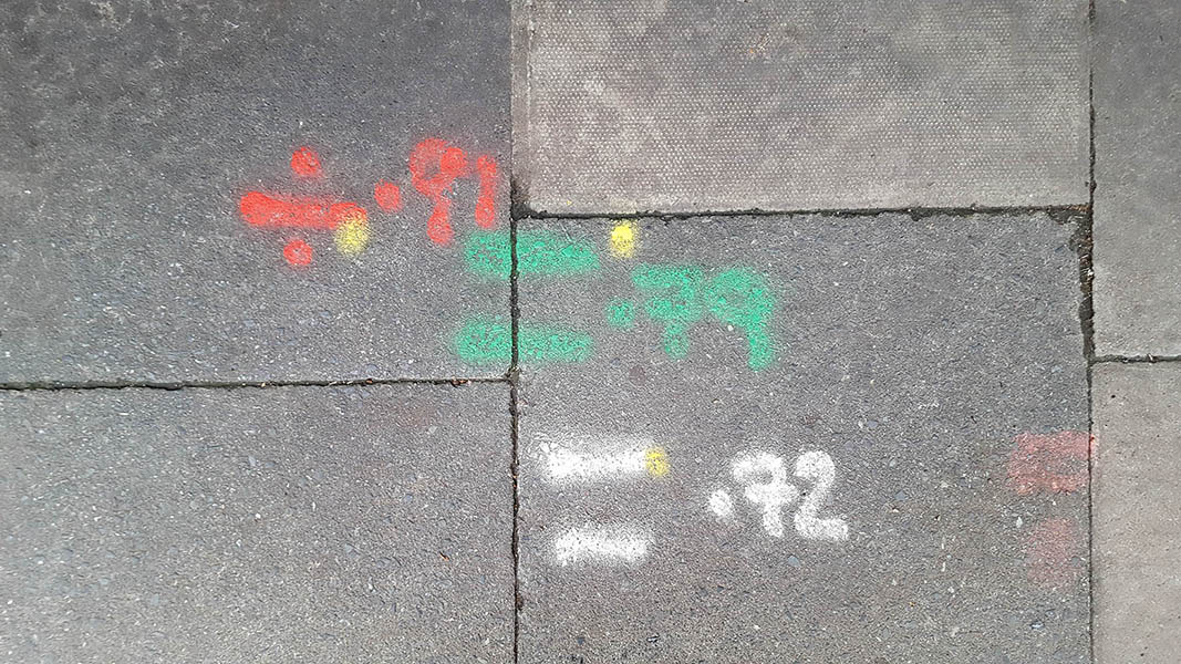 Pavement markings - spray painted squiggles on paving stones - Red green and white lines and numbers
