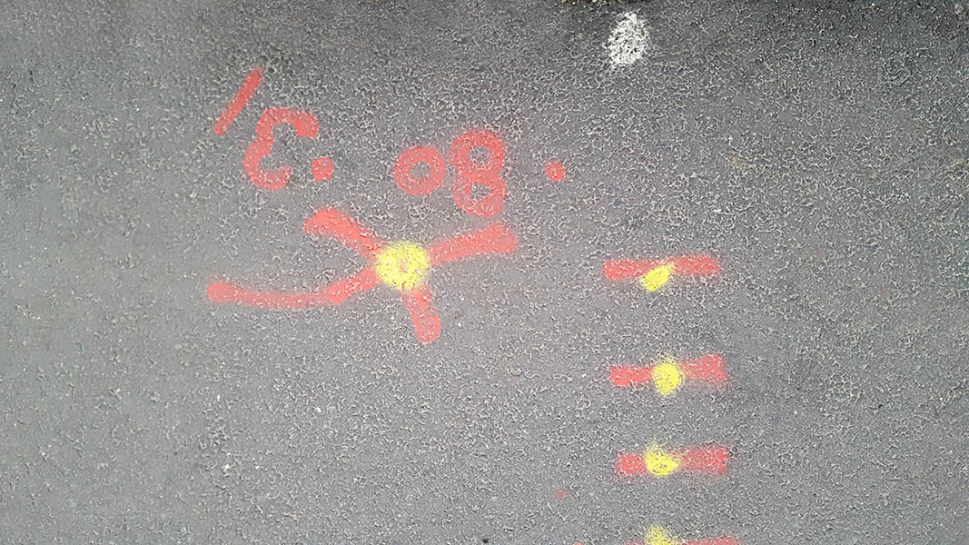 Pavement markings - spray painted squiggles on paving stones - Red lines and numbers and yellow dots
