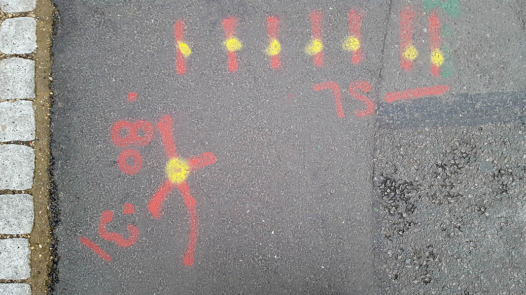 Pavement markings - spray painted squiggles on paving stones - Red lines and numbers and yellow dots