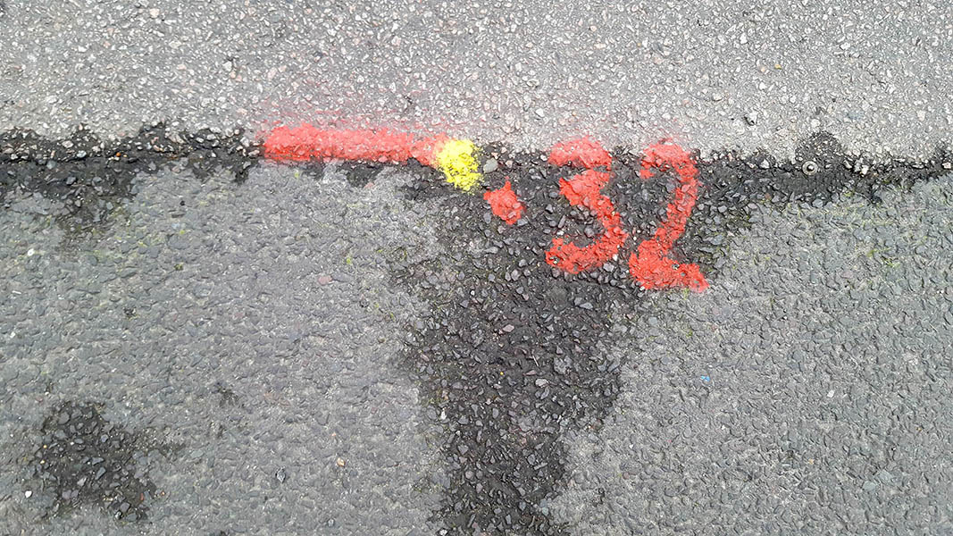 Pavement markings - spray painted squiggles on paving stones - Red 32 line and yellow dot