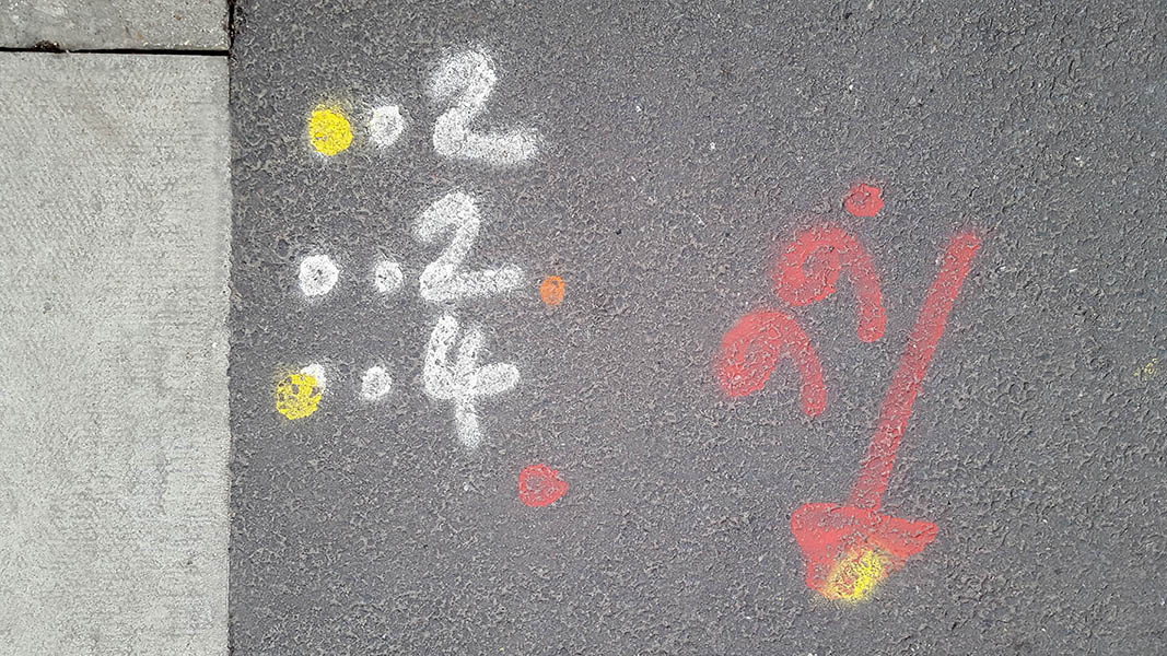Pavement markings - spray painted squiggles on paving stones - White red and yellow numbers dots and arrow