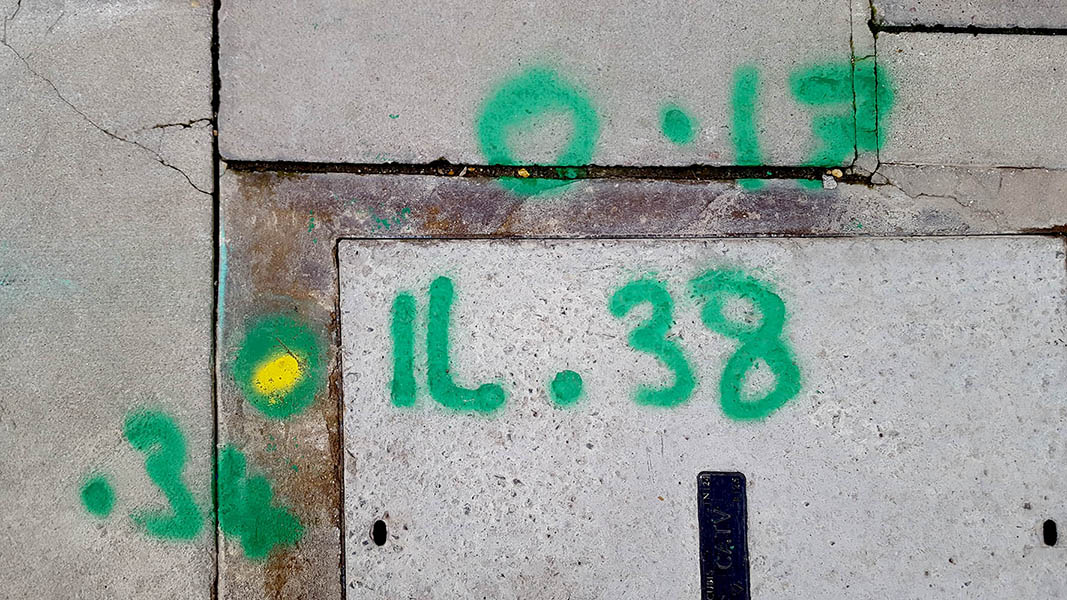 Pavement markings - spray painted squiggles on paving stones - Green letters and numbers with yellow dot