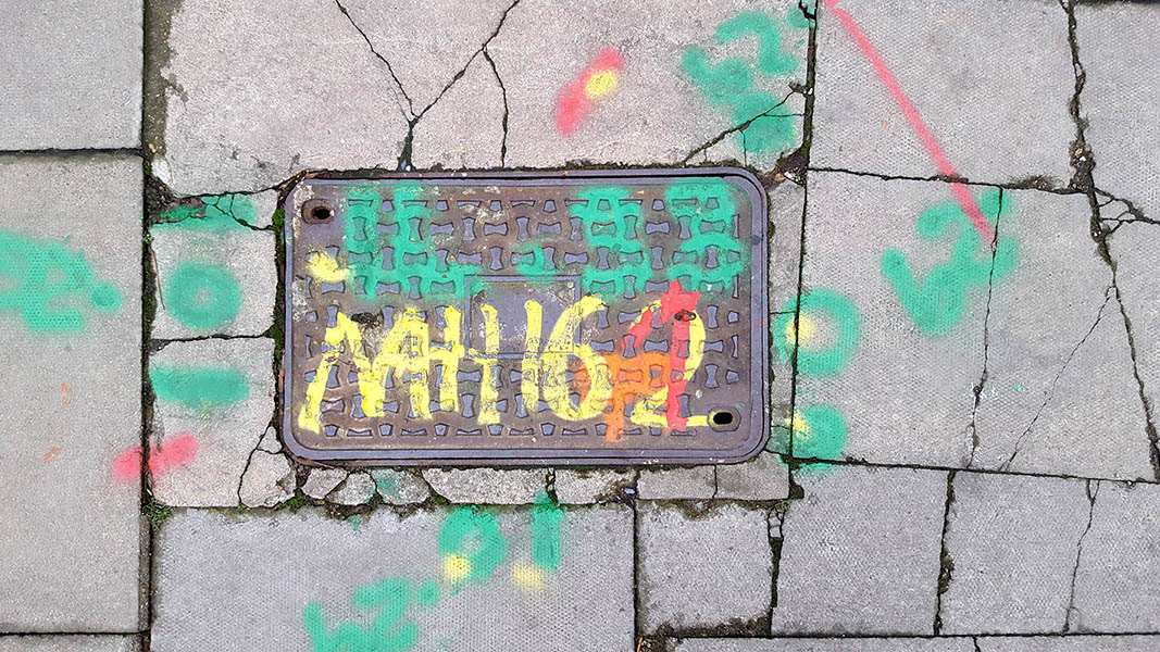 Pavement markings - spray painted squiggles on paving stones - Green yellow and red letters and numbers