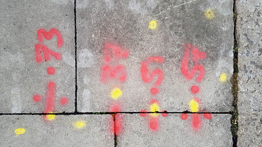 Pavement markings - spray painted squiggles on paving stones - Red numbers and yellow dots